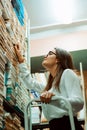 Student girl in the university library standing on the ladder, looking for a book