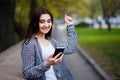 Young pretty stylish exulting woman holding smart phone in the s Royalty Free Stock Photo