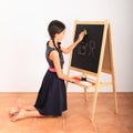 Girl erasing house and tree from black blackboard