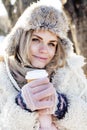 Young pretty teenage hipster girl outdoor in winter snow park having fun drinking coffee, warming up happy smiling Royalty Free Stock Photo