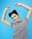 Young pretty teenage modern hipster girl posing emotional happy smiling on blue background, lifestyle people concept