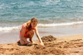 Young pretty teenager tanned girl building a sand castle on the beach near by sea Royalty Free Stock Photo