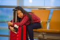 Young pretty tired and exhausted Asian Korean tourist woman in airport sleeping bored sitting at boarding gate hall waiting for de Royalty Free Stock Photo