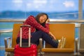 Young pretty tired and exhausted Asian Korean tourist woman in airport sleeping bored sitting at boarding gate hall waiting for de Royalty Free Stock Photo