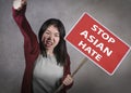 Young pretty and upset Korean woman holding stop Asian hate billboard in human rights defense screaming angry and furious against