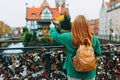 Young pretty woman with backpack standing and pointing to object on copy space, rear view against the Millers& x27; Guild