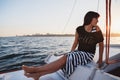 Young pretty woman in black shirt and striped skirt at luxury yacht in sea, sunset Royalty Free Stock Photo