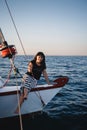 Young pretty woman in black shirt and striped skirt at luxury yacht in sea, sunset Royalty Free Stock Photo