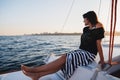 Young pretty woman in black shirt and striped skirt at luxury yacht in sea, sunset Royalty Free Stock Photo