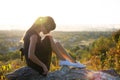 Young pretty woman in black short summer dress sitting on a rock relaxing outdoors at sunset. Fashionable female enjoying warm Royalty Free Stock Photo