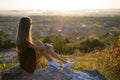 Young pretty woman in black short summer dress sitting on a rock relaxing outdoors at sunset. Fashionable female Royalty Free Stock Photo