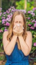 Young pretty woman blowing nose in front of blooming tree. Spring allergy concept VERTICAL FORMAT for Instagram mobile Royalty Free Stock Photo