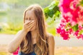 Young pretty woman blowing nose in front of blooming tree. Spring allergy concept Royalty Free Stock Photo