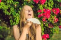 Young pretty woman blowing nose in front of blooming tree. Spring allergy concept Royalty Free Stock Photo
