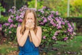 Young pretty woman blowing nose in front of blooming tree. Spring allergy concept Royalty Free Stock Photo