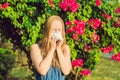 Young pretty woman blowing nose in front of blooming tree. Spring allergy concept Royalty Free Stock Photo