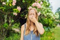 Young pretty woman blowing nose in front of blooming tree. Spring allergy concept Royalty Free Stock Photo