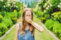 Young pretty woman blowing nose in front of blooming tree. Spring allergy concept Royalty Free Stock Photo