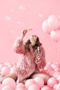 Young pretty woman blowing soap bubbles on pink background with balloons Royalty Free Stock Photo