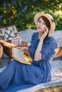 Young pretty girl holding book in lilac blooming garden