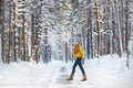 Young pretty woman in a bright clothes walks on a road in a winter forest Royalty Free Stock Photo