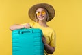 Young pretty woman with carry-on suitcase on yellow background. Teenager traveling with blue luggage bag for airplane Royalty Free Stock Photo