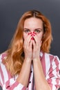 Pretty woman covers her face with hands with painted red nails Royalty Free Stock Photo