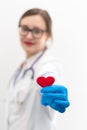 Young pretty woman doctor in a white medical coat and rubber gloves with a phonendoscope holds a red heart in her hands in a hospi Royalty Free Stock Photo