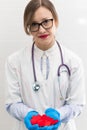 Young pretty woman doctor in a white medical coat and rubber gloves with a phonendoscope holds a red heart in her hands in a hospi Royalty Free Stock Photo