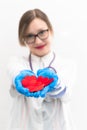 Young pretty woman doctor in a white medical coat and rubber gloves with a phonendoscope holds a red heart in her hands in a hospi Royalty Free Stock Photo