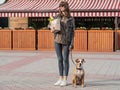 Young pretty woman with dog holds paper bag of groceries in front of market place or vegetable store. Going to shop for food with Royalty Free Stock Photo