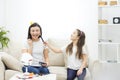 Young pretty woman doing make up while sitting with her little daughter in the living room. Royalty Free Stock Photo