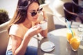 Young pretty woman drinking cappuccino, coffee in cafe outdoors