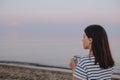 young pretty woman drinking hot morning tea looking at sunrise at sea Royalty Free Stock Photo