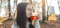 Young woman is drinking hot tea in an autumn Park in the light of the sunset. Cozy lifestyle in the autumn cold season Royalty Free Stock Photo