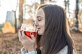 Young woman is drinking hot tea in an autumn Park in the light of the sunset. Cozy lifestyle in the autumn cold season Royalty Free Stock Photo