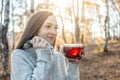 Young woman is drinking hot tea in an autumn Park in the light of the sunset. Cozy lifestyle in the autumn cold season Royalty Free Stock Photo