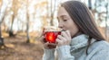 Young woman is drinking hot tea in an autumn Park in the light of the sunset. Cozy lifestyle in the autumn cold season Royalty Free Stock Photo