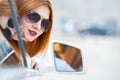 Young pretty woman driver in sunglasses looking out the car front window on a sunny summer day Royalty Free Stock Photo