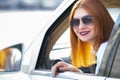 Young pretty woman driver in sunglasses looking out the car front window on a sunny summer day Royalty Free Stock Photo