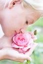 Young pretty woman enjoys smell of pink rose Royalty Free Stock Photo