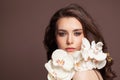 Young pretty woman face with healthy clear skin and white orchid flowers portrait. Facial treatment and skin care concept Royalty Free Stock Photo