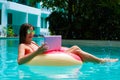 Young pretty woman freelancer is floating on the sea or in the pool in a swimming circle. A girl is relaxing on the Royalty Free Stock Photo