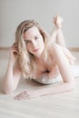 Young pretty woman in gentle lingerie on the floor, look at camera. Beauty portrait of female face with natural skin, no makeup. Royalty Free Stock Photo