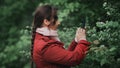 Young pretty woman or girl taking photo of flowers in green garden or park or forest with smartphone Royalty Free Stock Photo