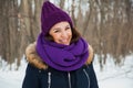 Young pretty woman with happy smile in purple snood and hand-knitted hat.