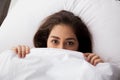 Young pretty woman hiding under blanket lying on bed Royalty Free Stock Photo