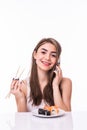 Young pretty woman holding chopstick eat sushi while talking on the mobile phone isolated on white background Royalty Free Stock Photo