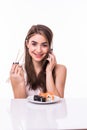 Young pretty woman holding chopstick eat sushi while talking on the mobile phone isolated on white background Royalty Free Stock Photo