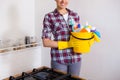 Young pretty woman holding cleaning tools and products in bucket